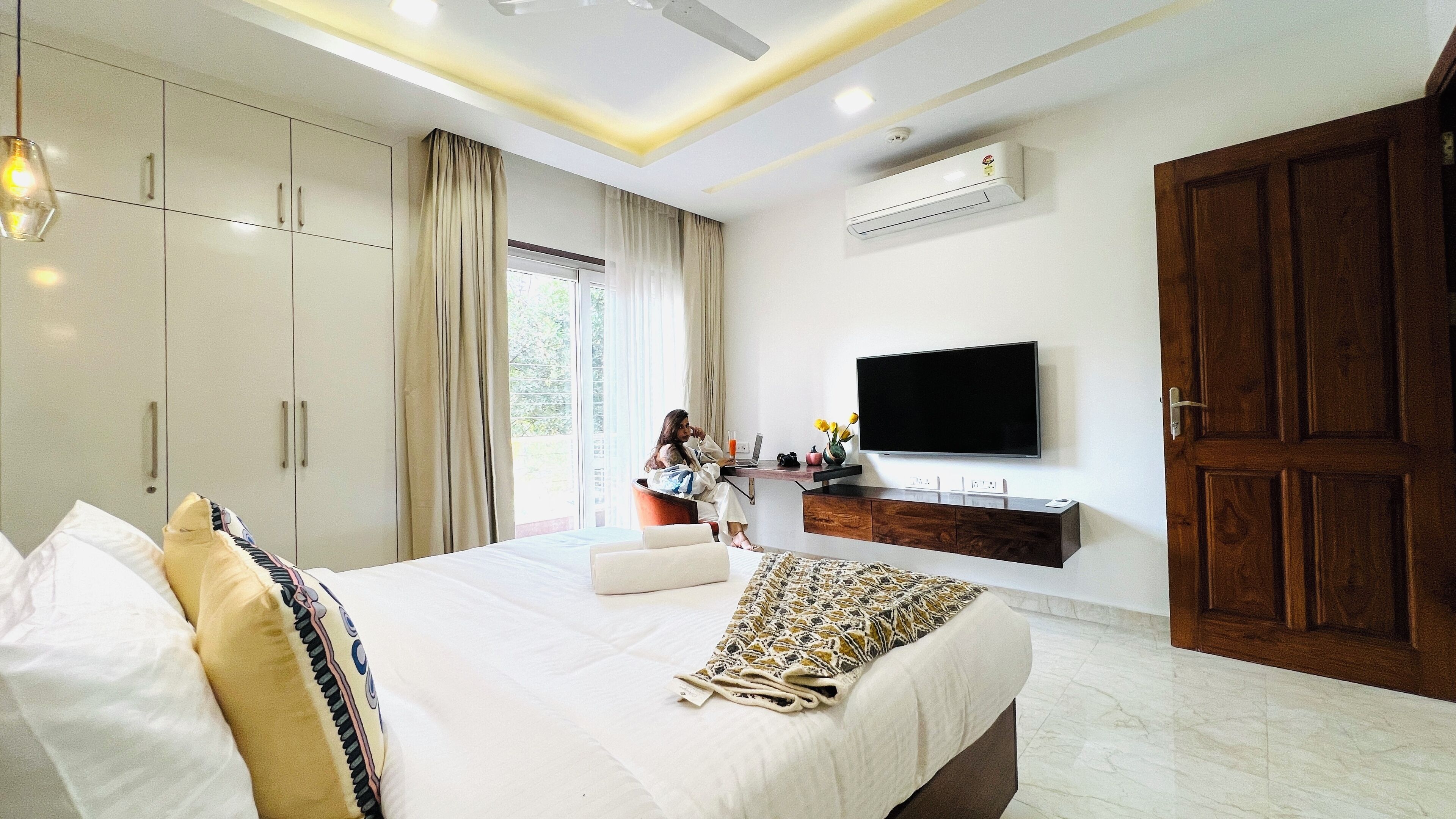 A modern bedroom with a large bed, a TV, and a wardrobe.
