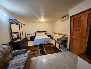 A bedroom with a bed, a chair, a dresser, a mirror, and a wardrobe. - Comfy Haven (Montego Bay)