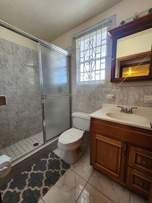 A bathroom with a shower, toilet, sink, and vanity. - Comfy Haven (Montego Bay)