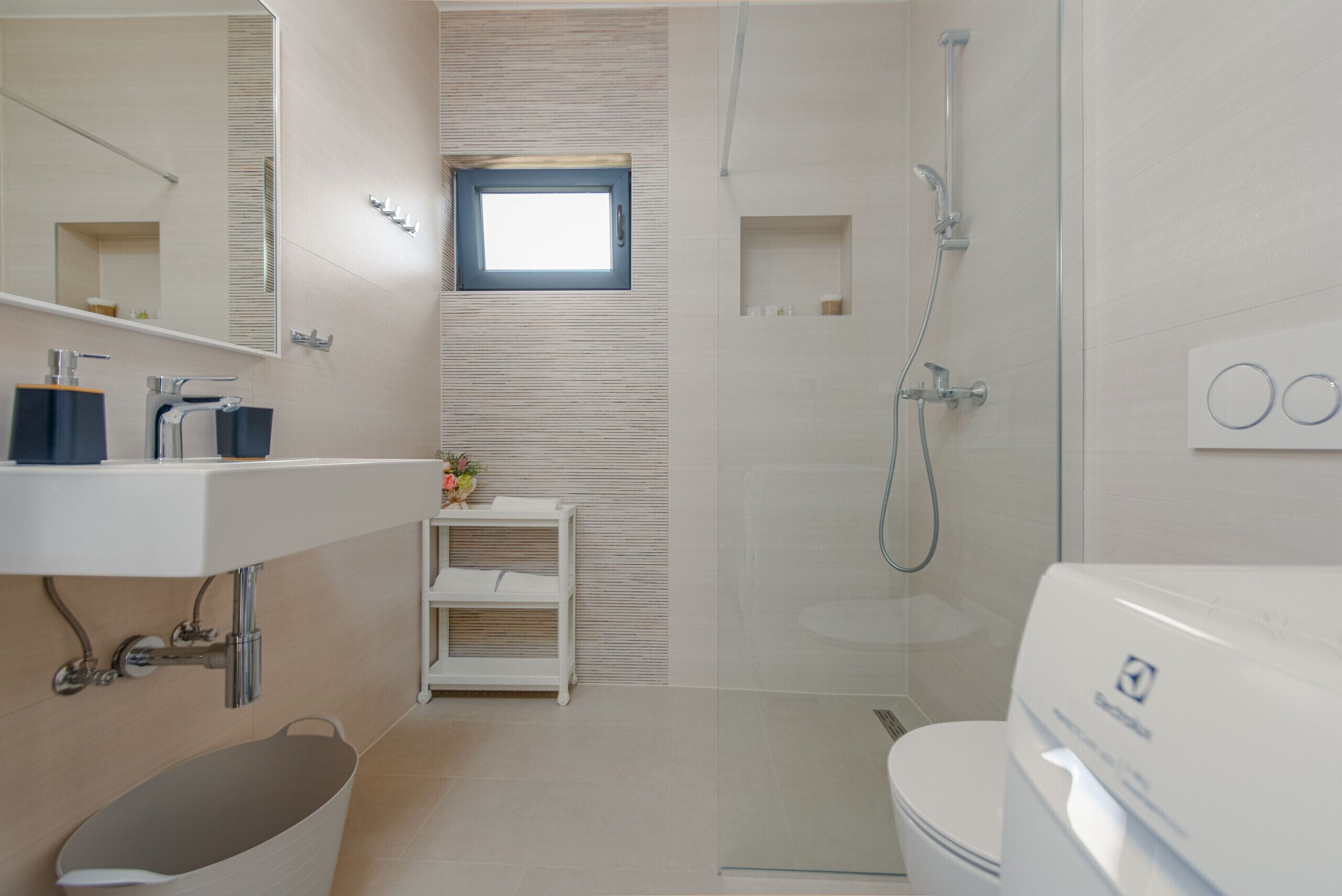 Une salle de bain moderne avec une douche à l’italienne en verre, un lavabo blanc avec un miroir et une baignoire.
