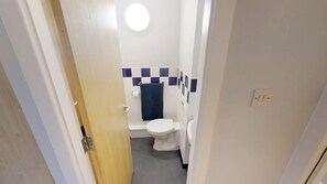 A small, compact bathroom with a toilet, a bathtub, and a shower area. - Great Newton House (Liverpool)
