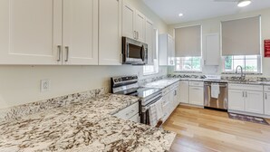 Una cocina moderna con armarios blancos, electrodomésticos de acero inoxidable y encimera de mármol.