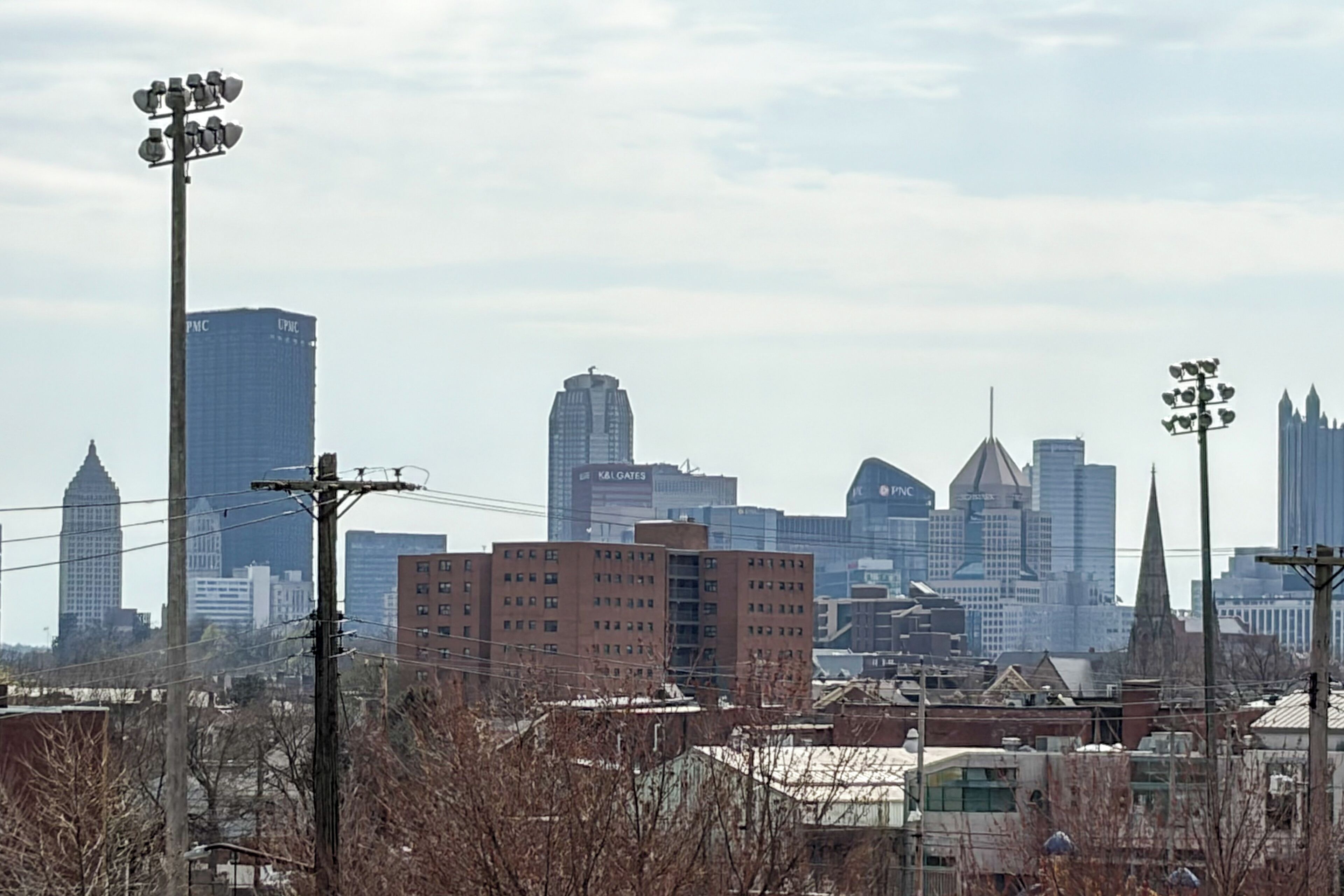 A city skyline with various buildings, including a prominent blue skyscraper and a red-brick building.