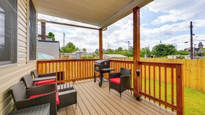Una terraza techada con mobiliario de mimbre y una parrilla.