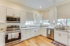 A modern kitchen with white cabinets, stainless steel appliances, and a wooden floor. - Pittsburgh Home w/ Skyline Views: Walk to Stadium! (Pittsburgh)