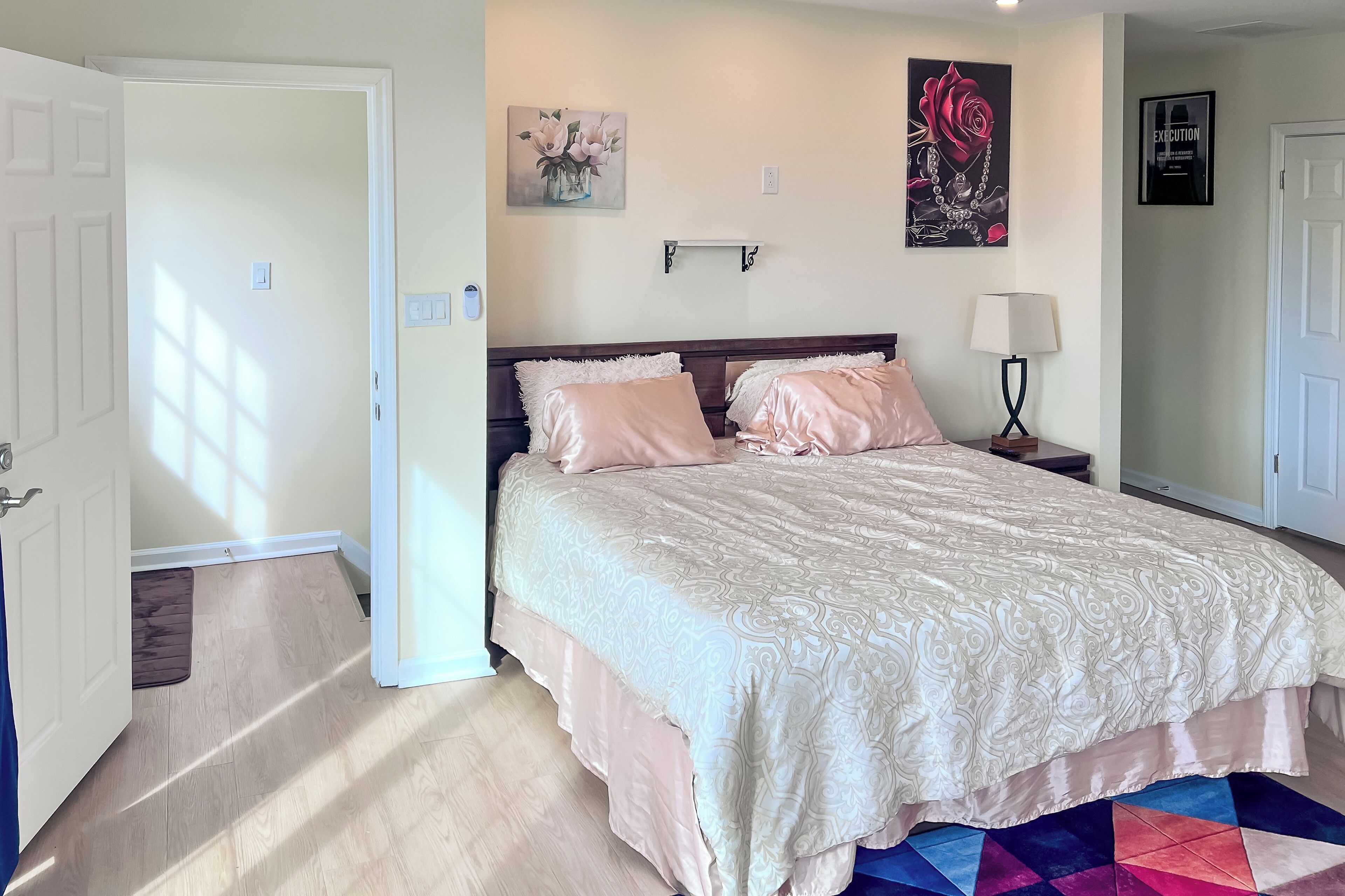 A bedroom with a bed, a nightstand, a lamp, and a wall-mounted shelf.