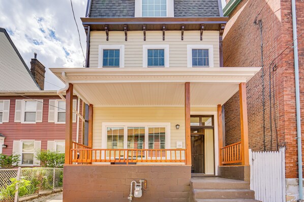A two-story house with a covered porch and a brick exterior. - Pittsburgh Home w/ Skyline Views: Walk to Stadium! (Pittsburgh)