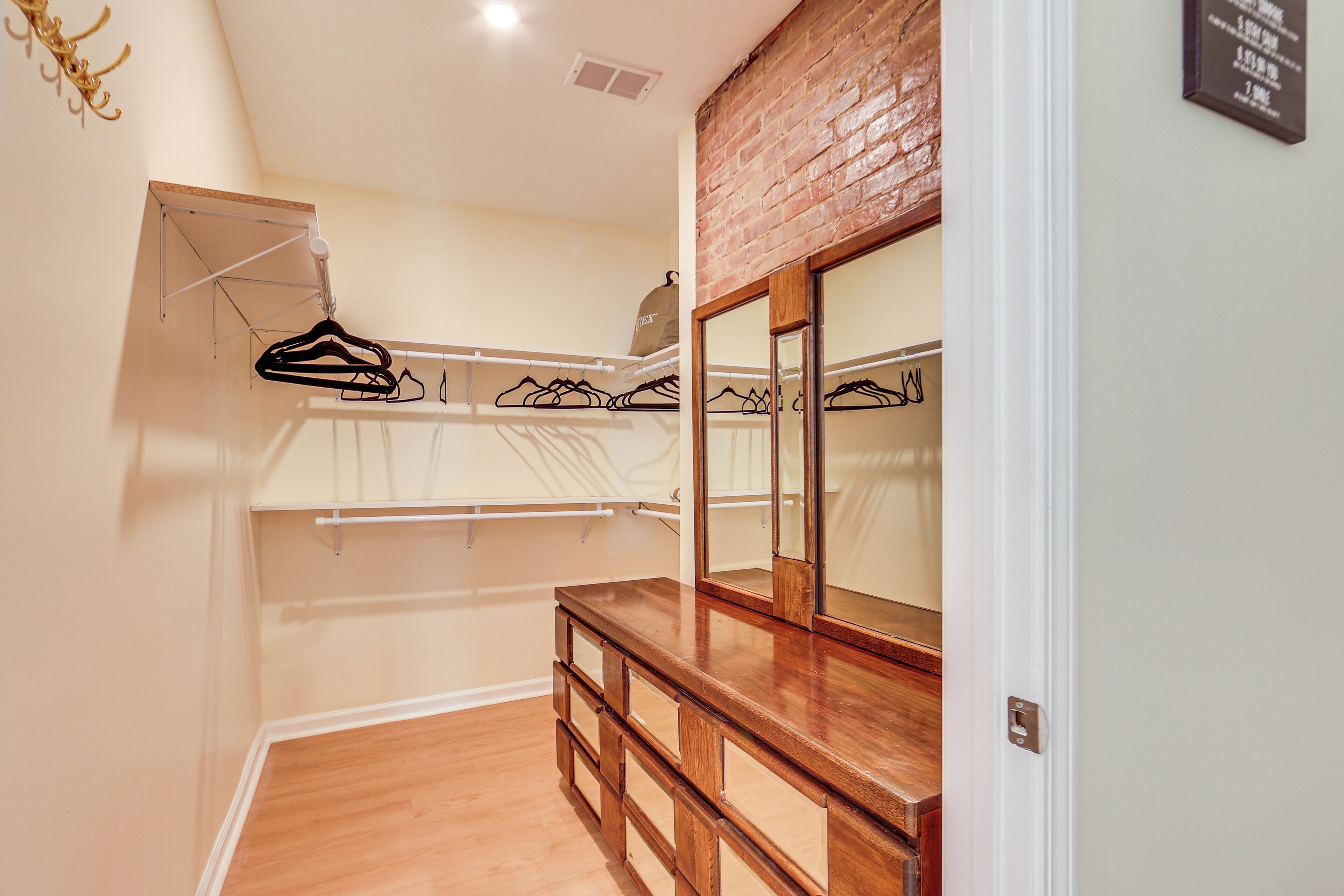 A walk-in closet with wooden drawers, a hanging rack, and a mirror.