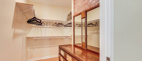 A walk-in closet with wooden drawers, a hanging rack, and a mirror.