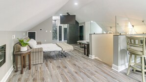 A loft-style bedroom with a sloped ceiling, a bed, a small table with a plant, and a chair. - Charlotte Home w/ Yard - Near Spectrum Center! (Charlotte)