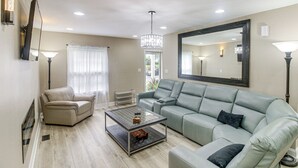 A living room with a beige sofa, a glass coffee table, and a grey sectional sofa. - Charlotte Home w/ Yard - Near Spectrum Center! (Charlotte)