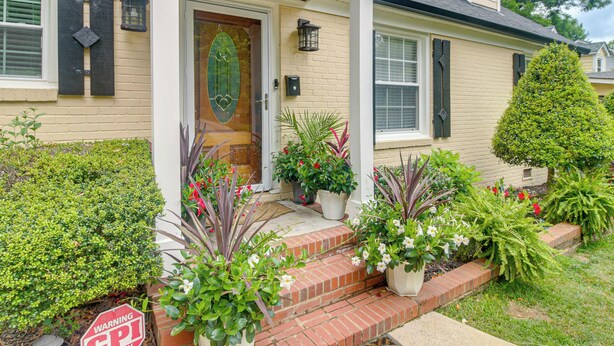 A house with a front porch, a wooden door, and potted plants. - Charlotte Home w/ Yard - Near Spectrum Center! (Charlotte)