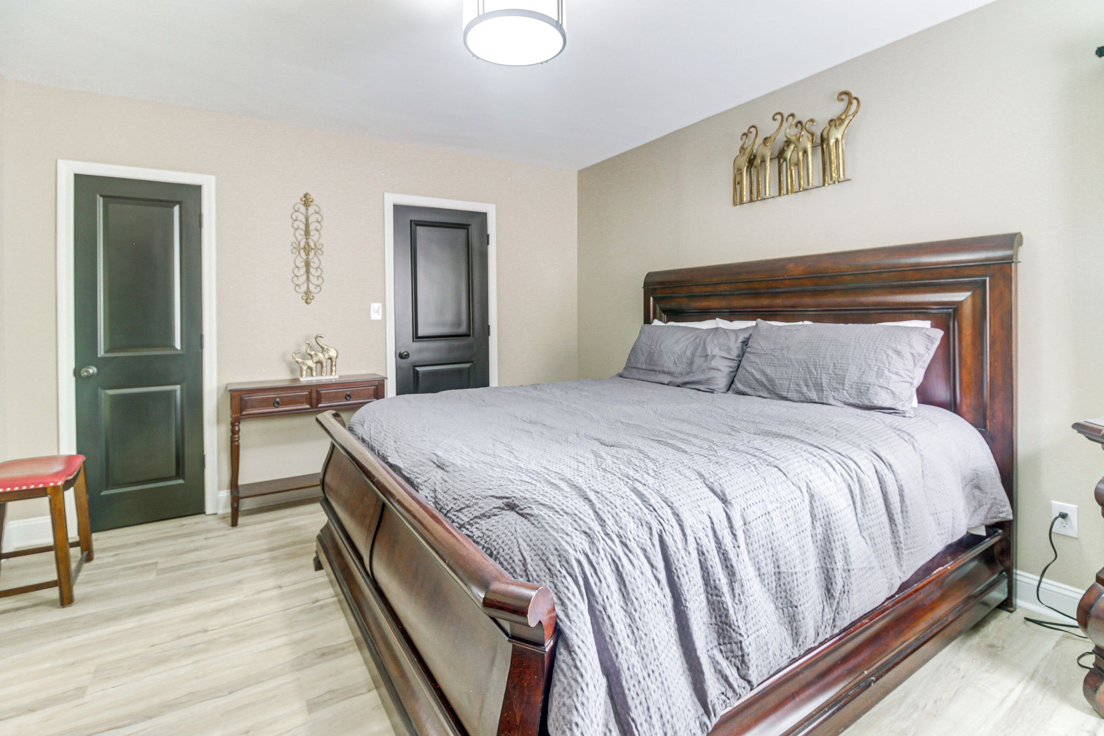 A bedroom with a wooden bed, a nightstand, a chair, and two doors.