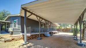 A covered outdoor area with a wooden deck, stone steps, and a building with a porch. - Snowy Peak Views & Cozy Game Nights: Pine Home (Pine)