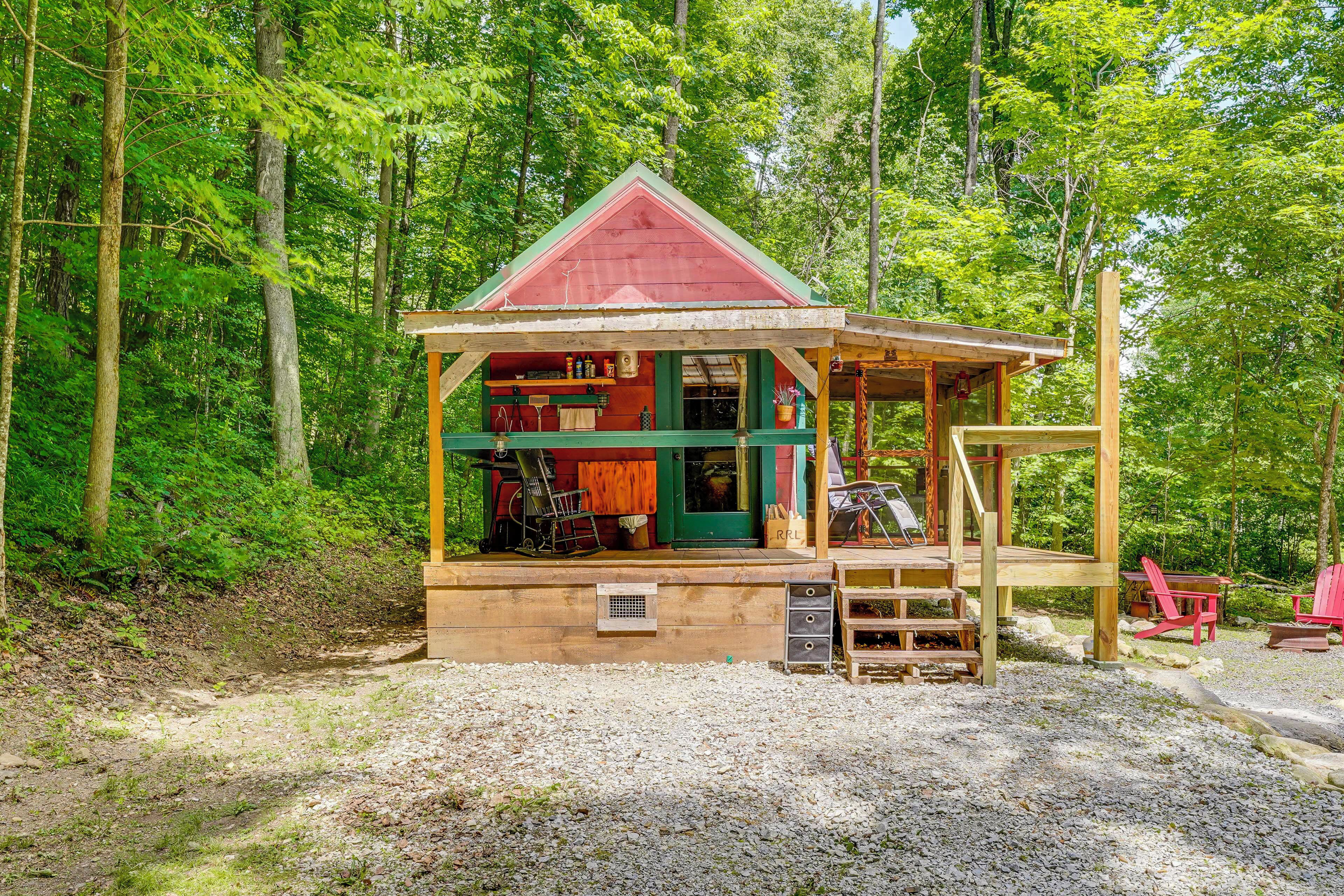 Une cabane avec un toit rouge, un revêtement extérieur en bois et une terrasse avec des chaises.