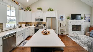 A modern kitchen with white cabinetry, a central island, a built-in microwave, and a stainless steel refrigerator.