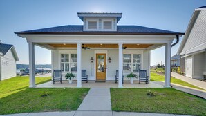 A two-story house with a covered porch, a front door, and a small garden area.