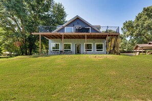 A two-story house with a balcony, large windows, and a wooden deck. - Frankston Vacation Rental: Walk to Lake Palestine! (Frankston)