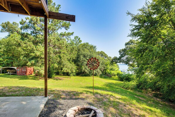A covered outdoor area with a fire pit, a wooden structure, and a metal wind chime. - Frankston Vacation Rental: Walk to Lake Palestine! (Frankston)