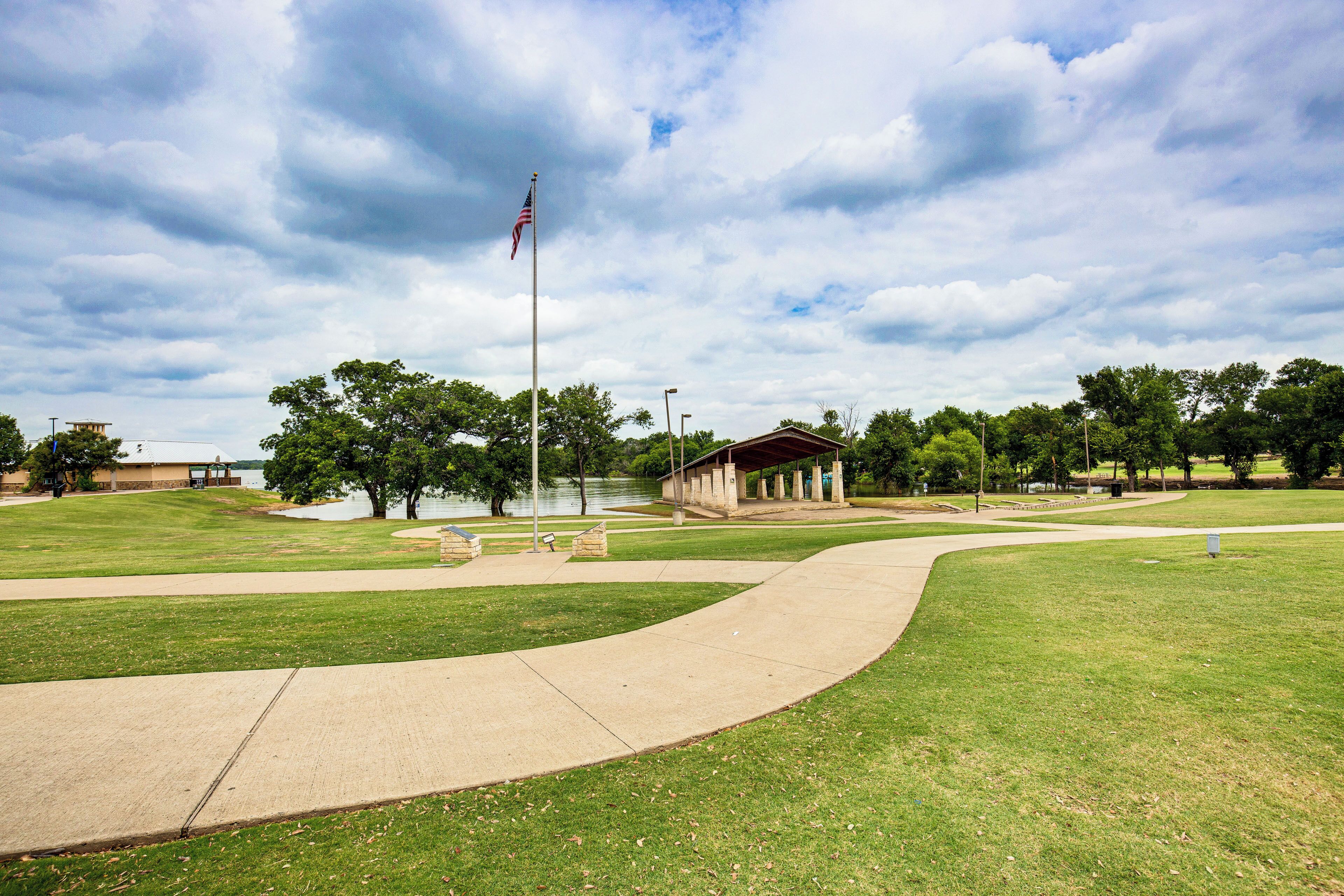 A park with a flagpole, a pavilion, and a curved walkway.