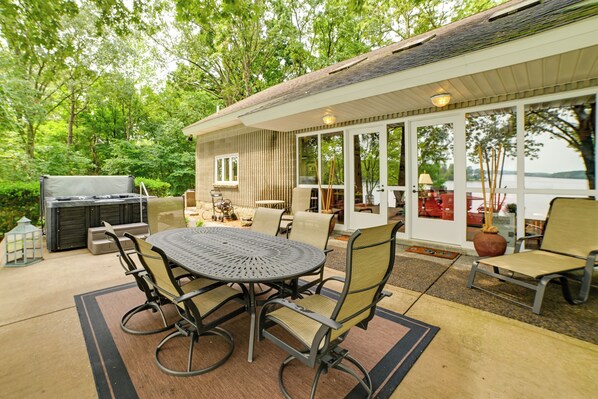 An outdoor patio with a round table and chairs, a grill, and a covered seating area with a view of the lake. - Boat Dock: Lakeside Kentucky Getaway! (Benton)