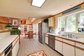 A kitchen with a refrigerator, dishwasher, and a window with a view of trees. - Boat Dock: Lakeside Kentucky Getaway! (Benton)