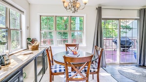 A dining area with a round table, four chairs, a chandelier, and large windows with a view of the outdoors. - Lovely Mccormick Home in Savannah Lakes Village (McCormick)