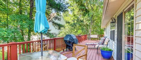 Une terrasse en bois avec une table et des chaises, un barbecue et un parasol bleu.