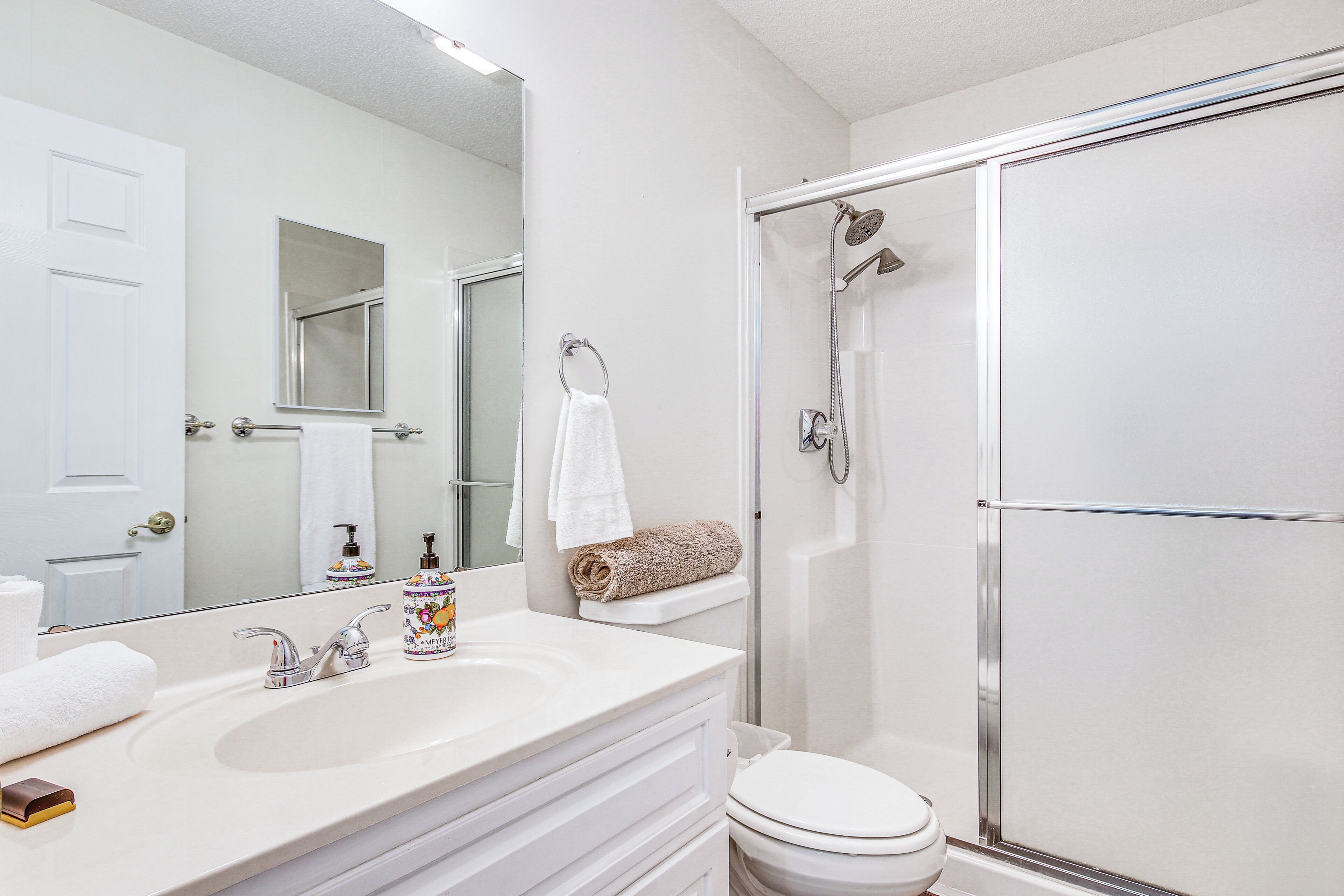 A bathroom with a white sink, a toilet, and a glass-enclosed shower.