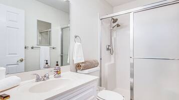 A bathroom with a white sink, a toilet, and a glass-enclosed shower.
