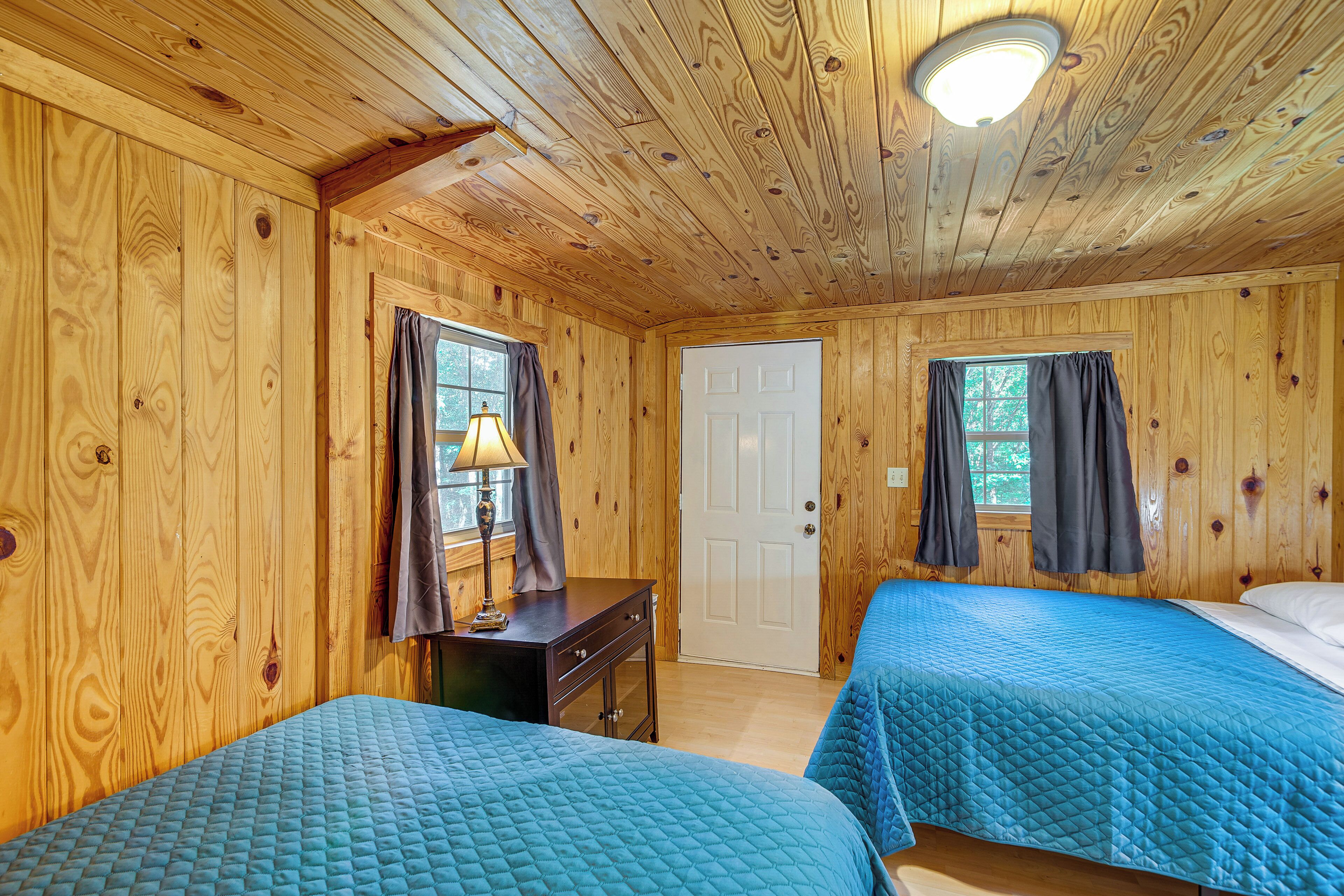 Ein Zimmer in einer Holzhütte mit zwei Betten, einem Schreibtisch und einer Tür.