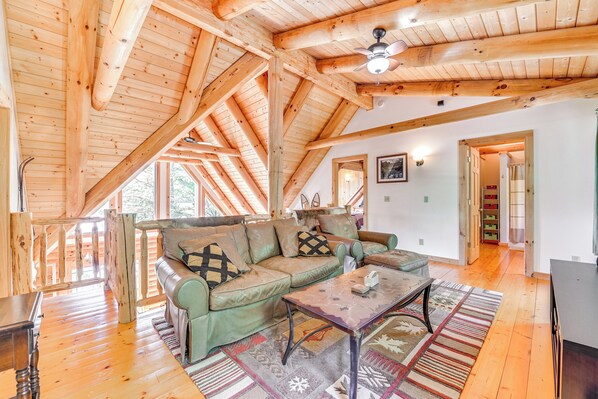 A cozy wooden interior with a sofa, coffee table, and a ceiling fan. - Lakefront Corinth Log Home: Private Dock, Fire Pit (Corinth)