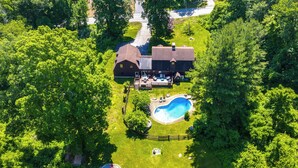 Luftaufnahme eines Hauses mit großem Garten, einem Schwimmbecken und einem eingezäunten Deckbereich.