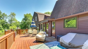Eine Terrasse mit Gartenmöbeln, einem überdachten Grill und Blick auf die Umgebung.