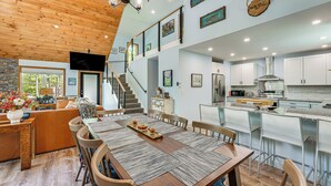 A spacious kitchen with modern appliances, a dining area with a wooden table and chairs, and a staircase leading to an upper level. - Near Hiking Trails & Ski Resorts: Killington Home! (Killington)