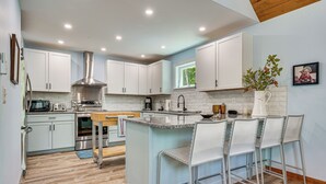 A modern kitchen with white cabinets, stainless steel appliances, and a central island with bar stools. - Near Hiking Trails & Ski Resorts: Killington Home! (Killington)