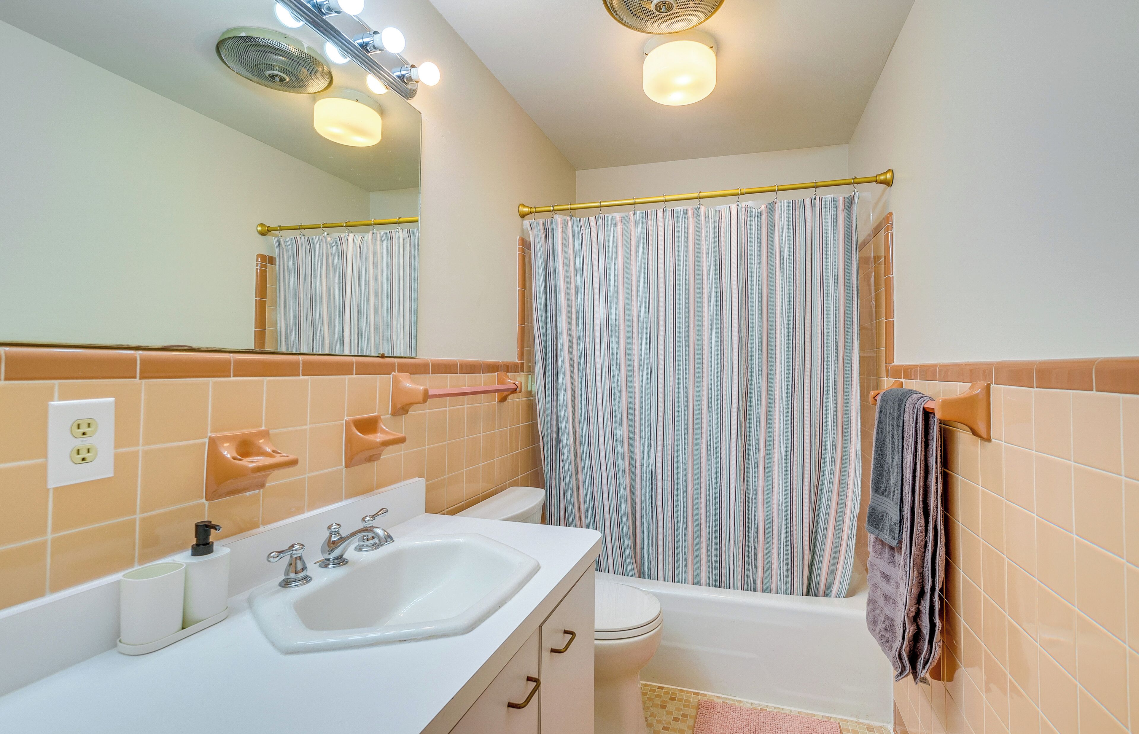 Une salle de bain avec un lavabo blanc, des toilettes, une baignoire et un rideau de douche.