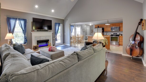A spacious living room with a fireplace, a large TV, and a ceiling fan. - Unicoi Wine Trail Retreat! Bbq-ready Deck w/ Views (Sautee Nacoochee)
