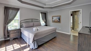 A bedroom with a bed, nightstands, a ceiling fan, and a door leading to another room. - Unicoi Wine Trail Retreat! Bbq-ready Deck w/ Views (Sautee Nacoochee)