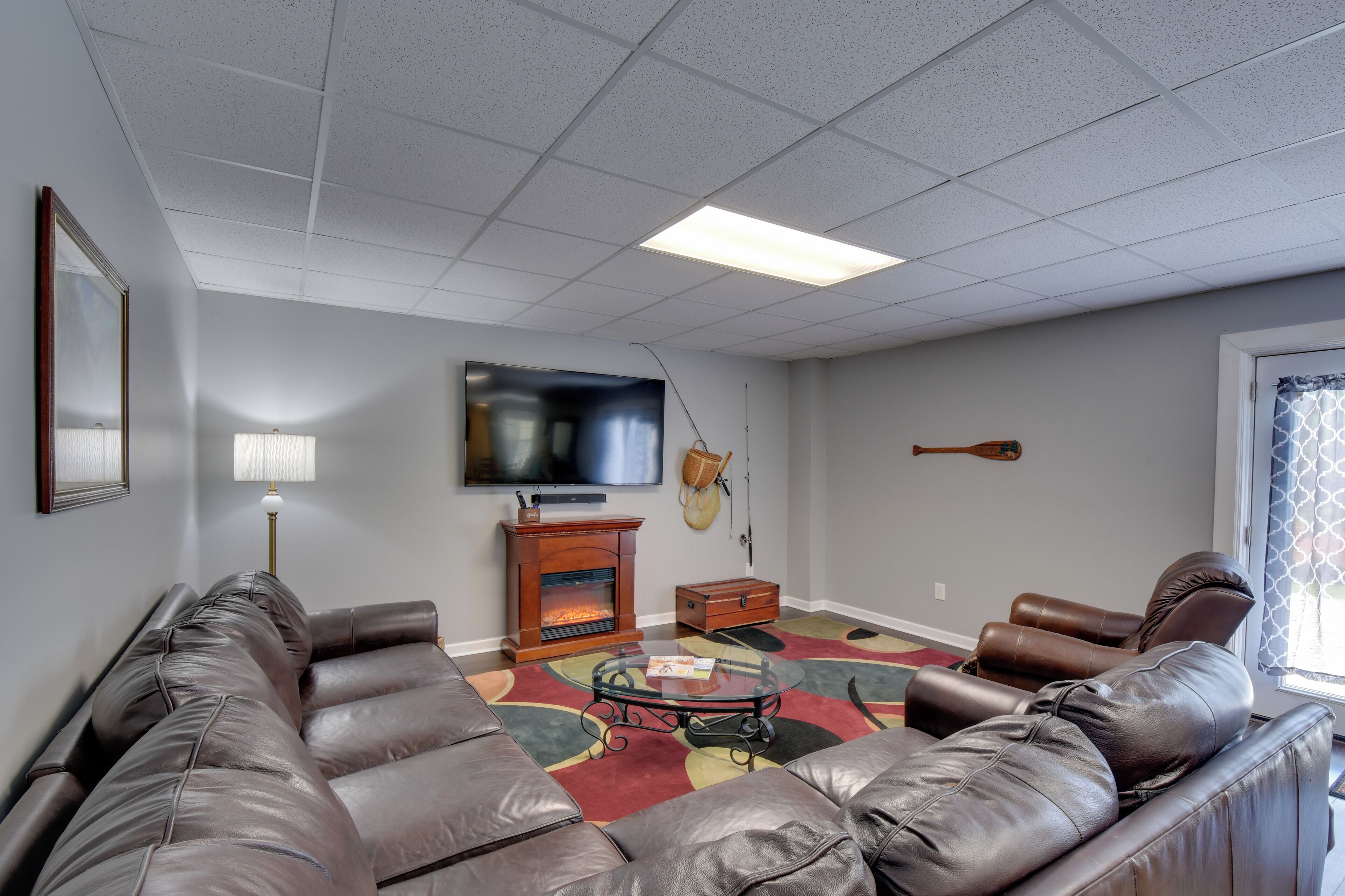 A living room with a leather sofa, a glass coffee table, a fireplace, and a flat-screen TV.