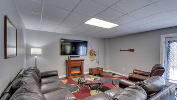 A living room with a leather sofa, a glass coffee table, a fireplace, and a flat-screen TV.