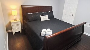 A neatly made bed with a dark headboard, a bedside lamp, and a white door in the background. - Wine Trail Apt 7 Mi to Yonah Mtn! Patio & Views (Sautee Nacoochee)
