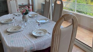 A dining area with a table set for four, chairs, and a view of a residential building through large windows. - 4-person air-conditioned apartment with beach and all amenities within walking distance (Saint-Raphaël)