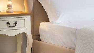 Un lit bien fait, avec une tête de lit, une table de chevet dotée d’une lampe et un petit tiroir.