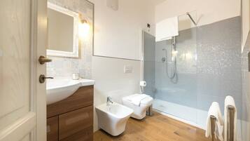 Ein modernes Badezimmer mit einem Holzlagerflächen, einem Bidet, einer Toilette und einer gläsernen Duschkabine.