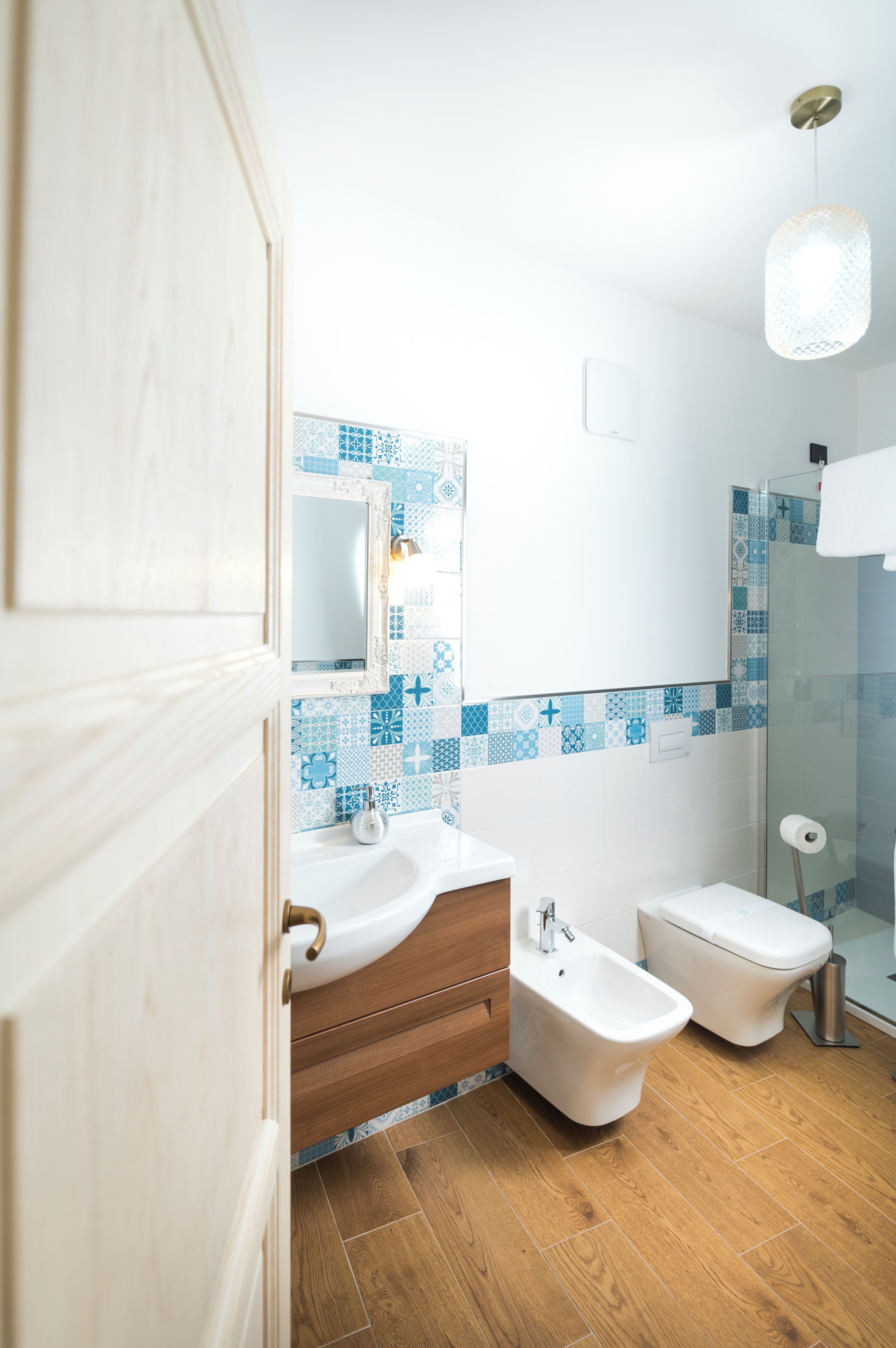 Un baño moderno con tocador de madera, un bidé, un inodoro y una zona de ducha.