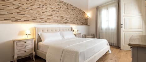 A bedroom with a large bed, a nightstand with a lamp, a wooden headboard, and a wardrobe.