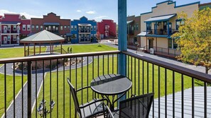 En balkong med ett bord och stolar, en pergola och utsikt över färgglada byggnader.