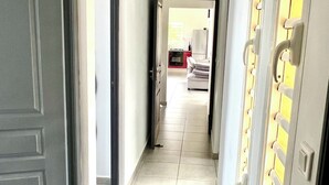 A hallway with a tiled floor, a door on the left, and a wall with multiple storage units on the right. - Villa Tropical Quintet. 3 bedrooms. Sea view. Pool. Leroux beach at 800 m. (Deshaies)