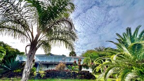 A house with a covered porch, surrounded by lush greenery and a stone wall. - Villa Tropical Quintet. 3 bedrooms. Sea view. Pool. Leroux beach at 800 m. (Deshaies)